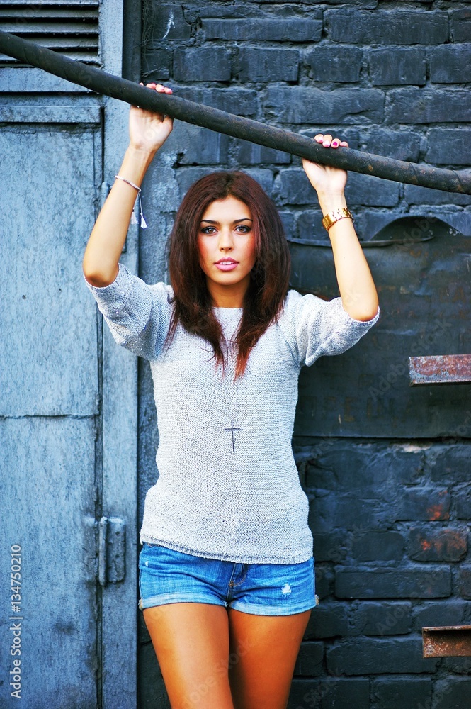 Young beautiful tanned brunette girl in jumper and short denim