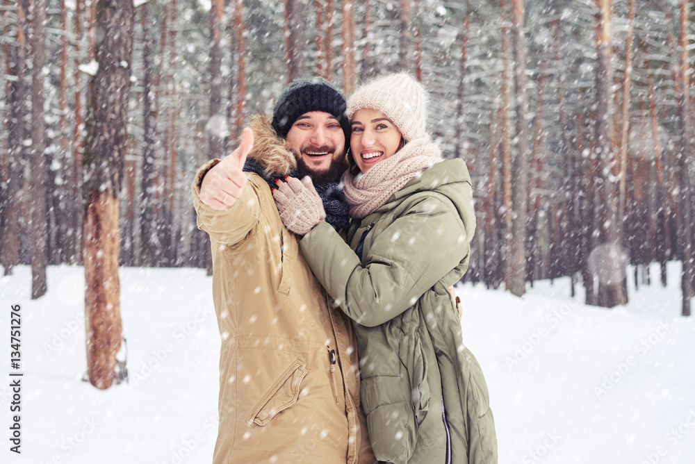 Cheer husband showing thumb up and embraces wife over a pictures Cheer husband showing thumb up and embraces wife over a pictures