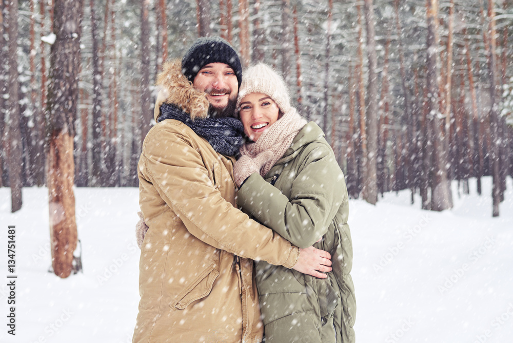 Middle-aged couple embrace while enjoying a winter walk through Middle-aged couple embrace while enjoying a winter walk through
