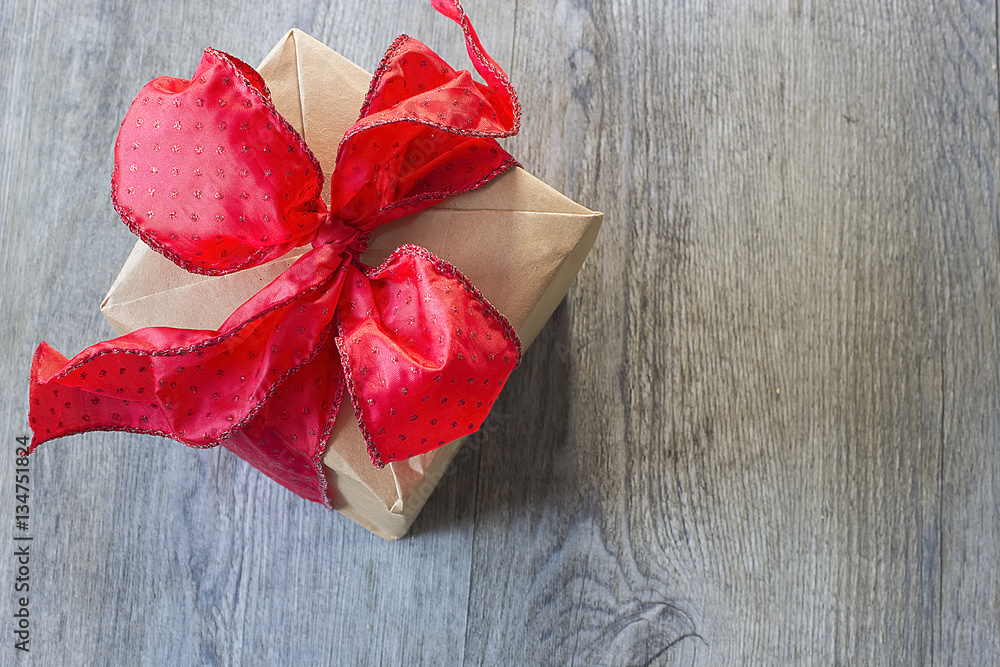 A gift with red bow on gray wooden background A gift with red bow on gray wooden background