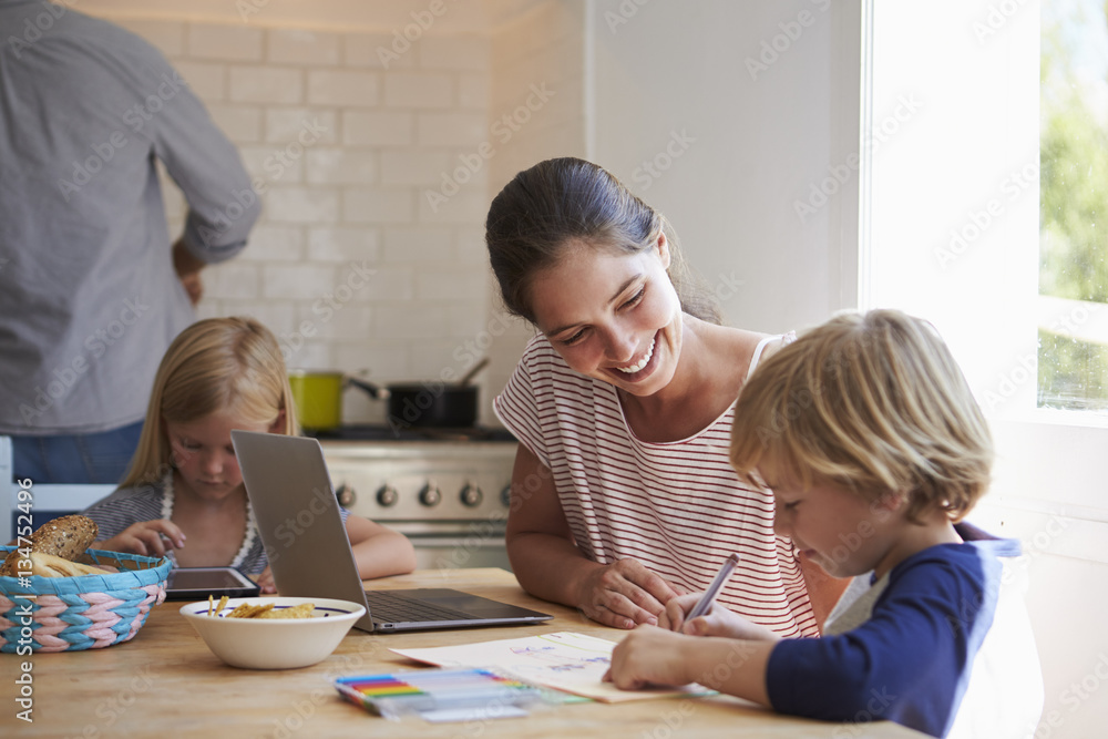Kids doing homework at kitchen table with mum, close up Kids doing homework at kitchen table with mum, close up