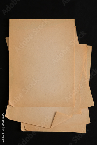 old craft paper sheets pile isolated on black background