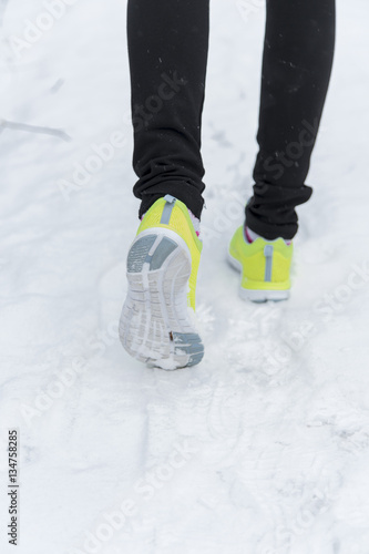 Running sport woman. Female runner jogging in cold winter forest wearing warm sporty running clothing and gloves headphones. Beautiful fit female fitness model.