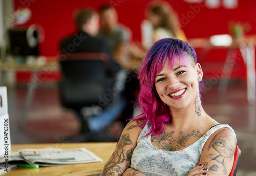 Confident female designer working in red creative office space