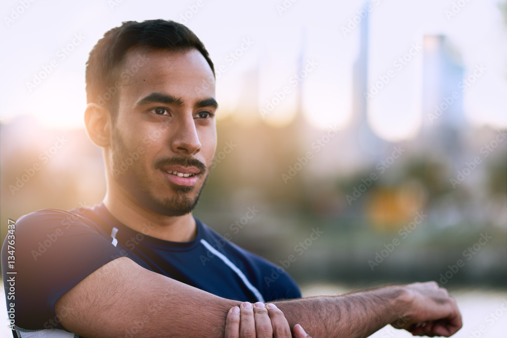 Φωτογραφία Portrait of active millenial man jogging at dusk with an urban cityscape and sun