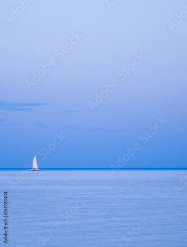 Lonely yacht on horizon. Sailing boat between the sky and sea