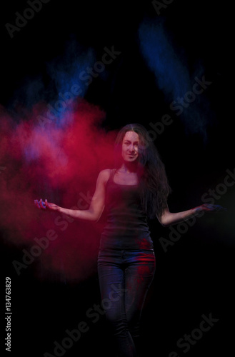 A young girl stands in a cloud of red and blue paint holy.