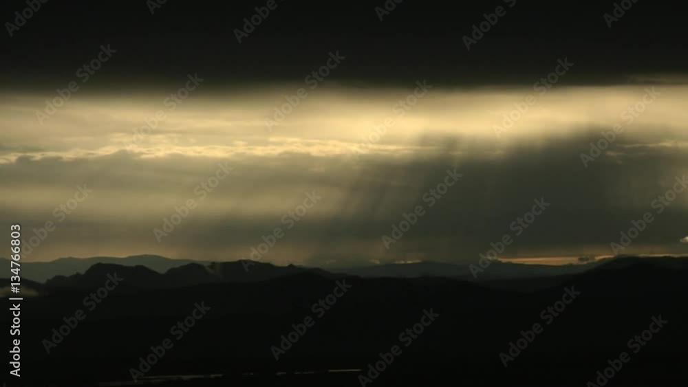 Sun Rays Beam Down from Dark Clouds over Mountain Sun Rays Beam Down from Dark Clouds over Mountain