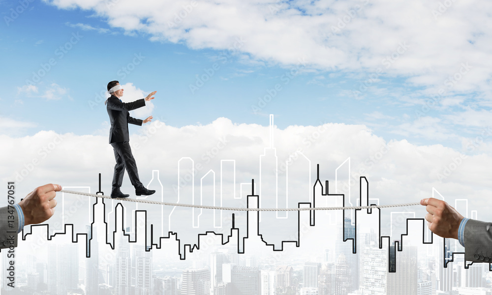 Business concept of risk support and assistance with man balancing on rope Business concept of risk support and assistance with man balancing on rope
