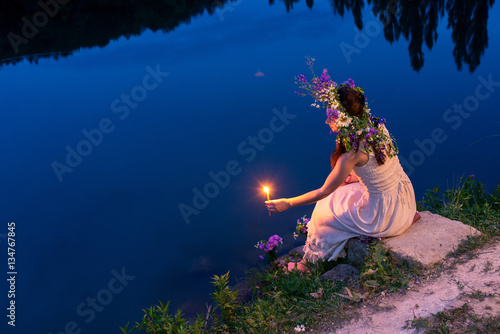 girl in a wreath with a candle sitting by the river