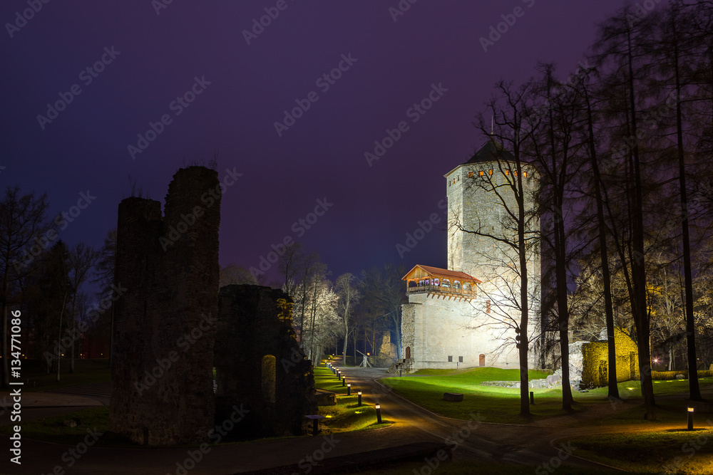 Keep - main tower of Paide castle in Estonia. Green park at ruins of castle. Night illuminated view.