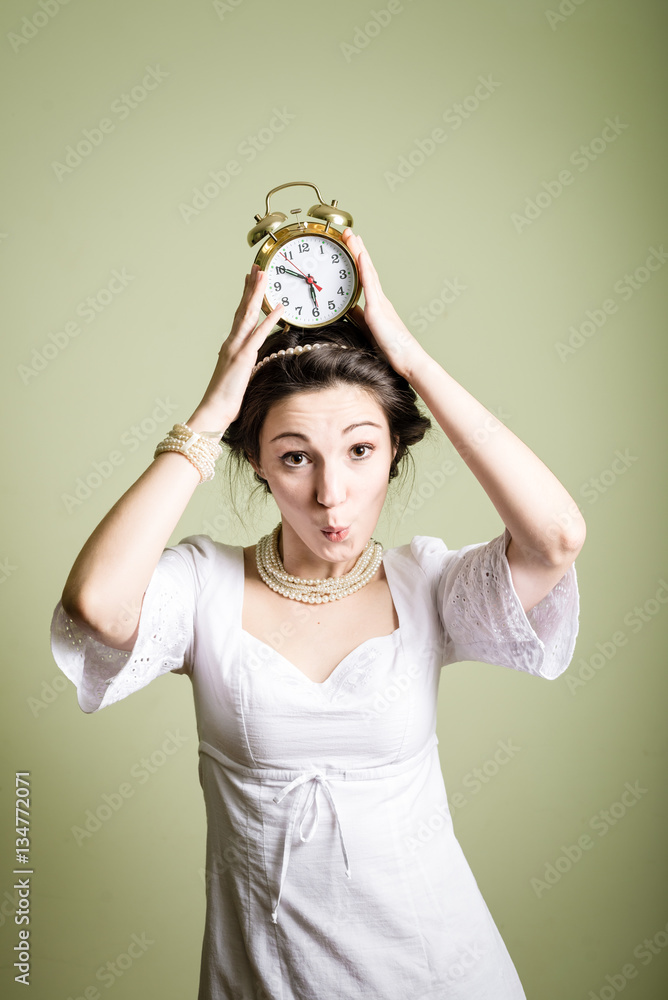 Joyful beautiful woman holding up alarm clock over light background. Portrait Joyful beautiful woman holding up alarm clock over light background. Portrait