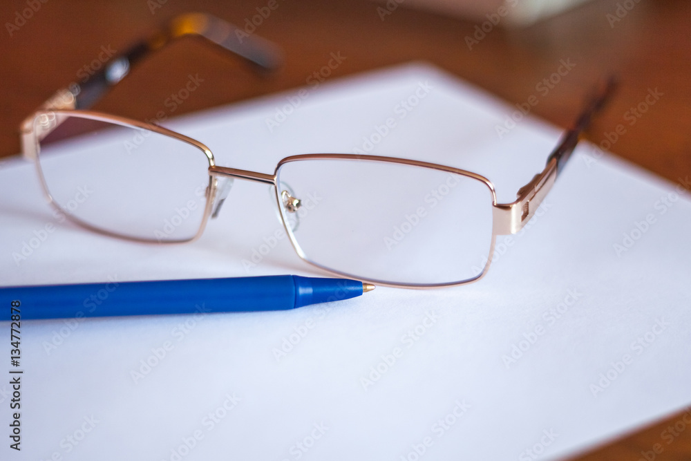 ballpoint pen on a sheet and reading glasses with box ballpoint pen on a sheet and reading glasses with box