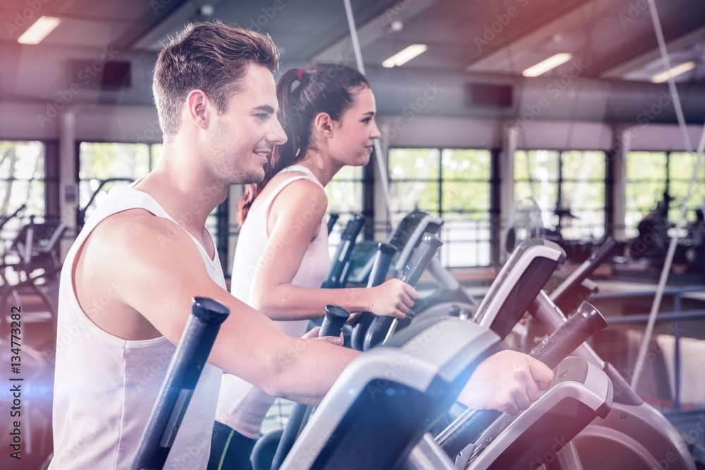 Beautiful woman and man exercising on elliptical machine Beautiful woman and man exercising on elliptical machine
