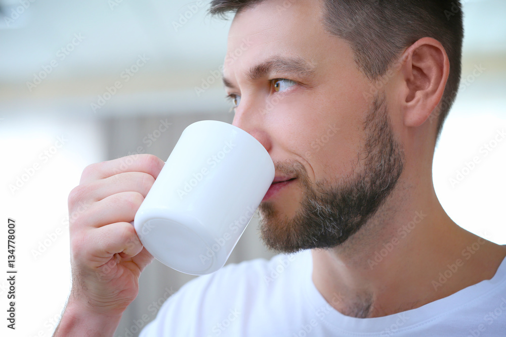 Handsome young man drinking coffee at home, closeup Handsome young man drinking coffee at home, closeup