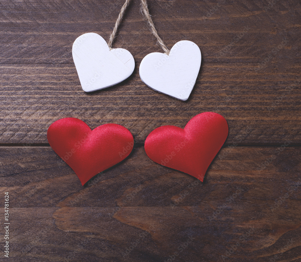 Fototapeta premium Two white hearts and two red hearts on brown wooden table