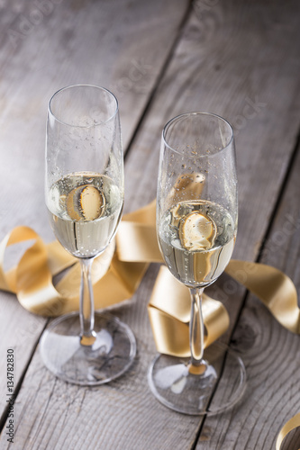 two champagne glasses with gold ribbon on wood board.valentines