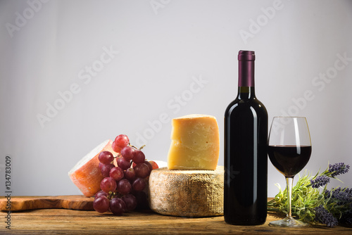 Red wine in vintage light with cheese and fruits.