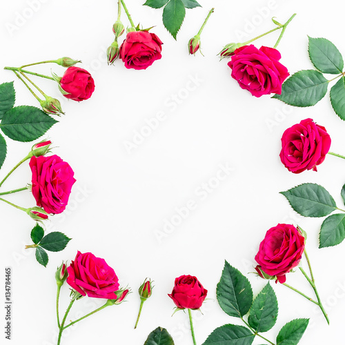 Round frame with red roses  branches  leaves and petals isolated on white background. flat lay  overhead view
