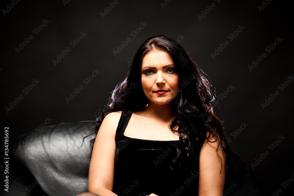 Fototapeta premium Young Woman Sitting In A Black Armchair