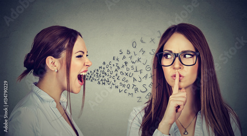 Angry woman screaming at herself with quiet finger on lips gesture photo
