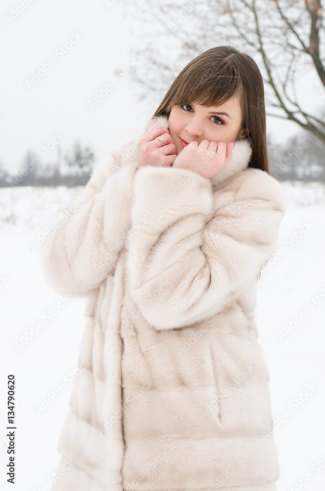 Beauty joyful teenage model girl having fun in winter park. Beautiful young woman in a fur coat outdoors. Enjoying nature. Beauty joyful teenage model girl having fun in winter park. Beautiful young woman in a fur coat outdoors. Enjoying nature.