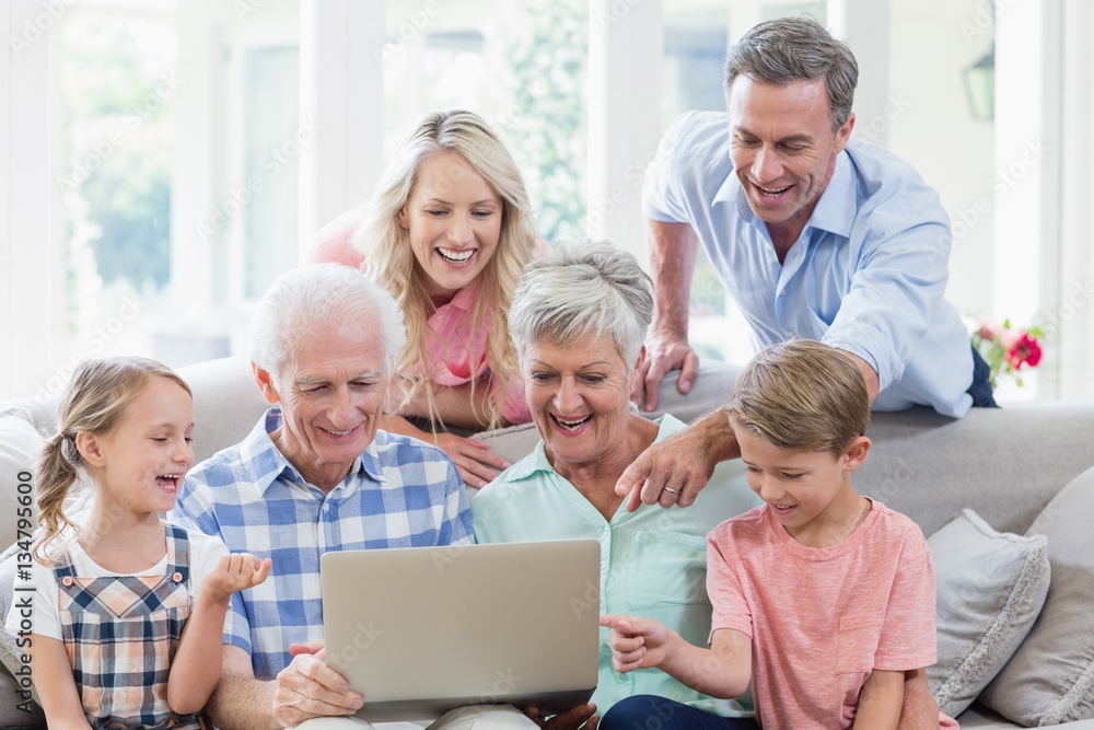 Happy multi-generation family using laptop in living room Happy multi-generation family using laptop in living room