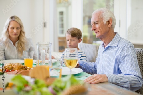 Multi-generation family praying before having meal