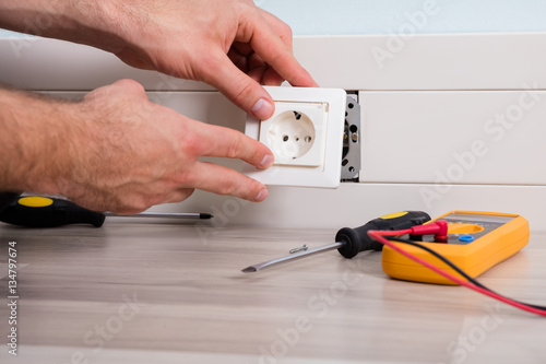 Person's Hand Installing Socket On Wall