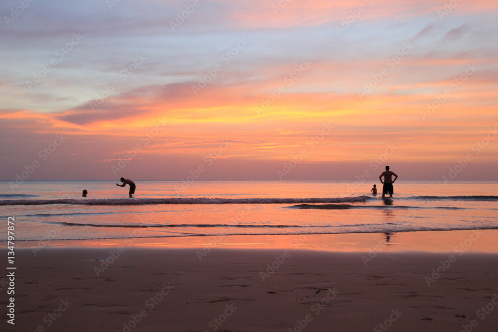 Koh Chang, Thailand. The walking people on the beach on the colorful sunset.