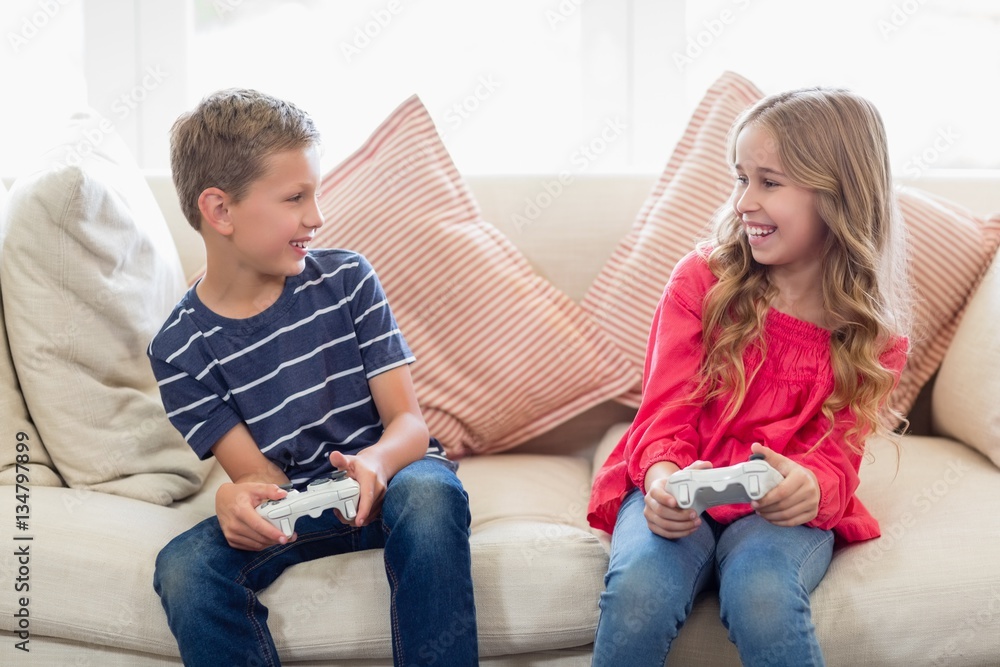 Siblings playing video games in living room Siblings playing video games in living room