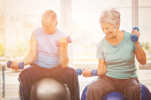 Smiling senior couple holding dumbbells while exercising