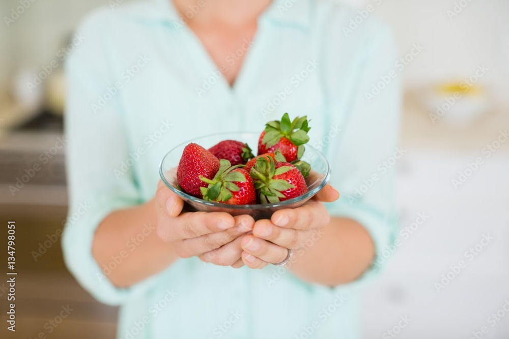 Beautiful woman holding glass of strawberry in kitchen Beautiful woman holding glass of strawberry in kitchen