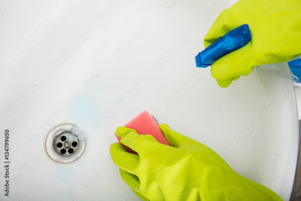 Person Cleaning The Basin Of The Bathroom