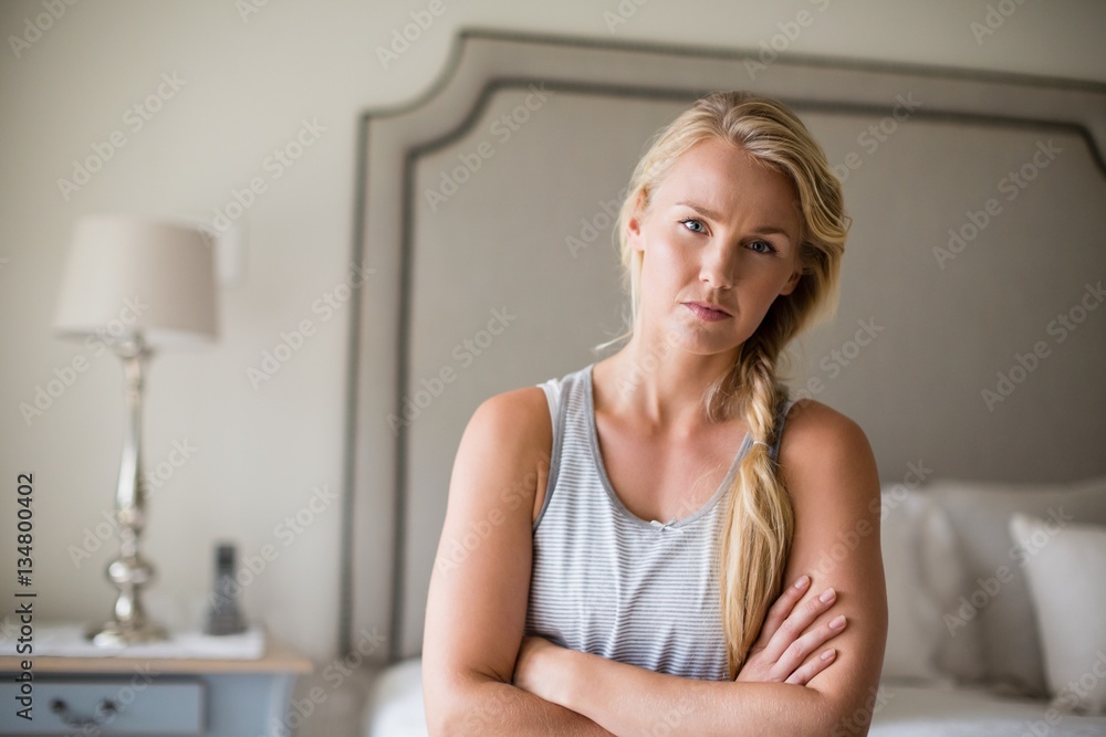 Beautiful woman sitting on bed with arms crossed in bedroom Beautiful woman sitting on bed with arms crossed in bedroom