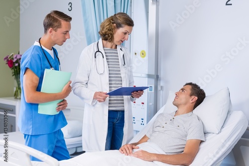 Doctors talking to patient in hospital bed