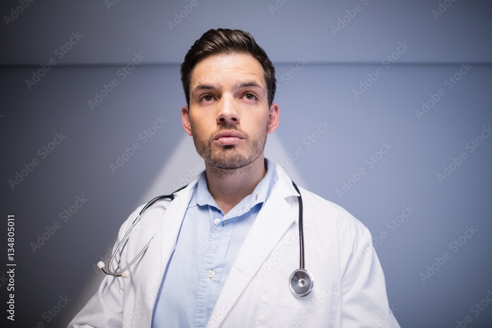 Thoughtful doctor standing in corridor Thoughtful doctor standing in corridor