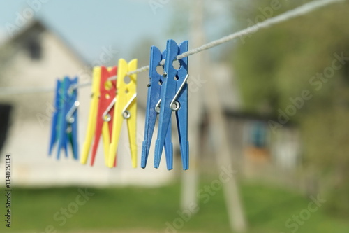 Colorful clothes pins on rope. Art concept on blurred country house background