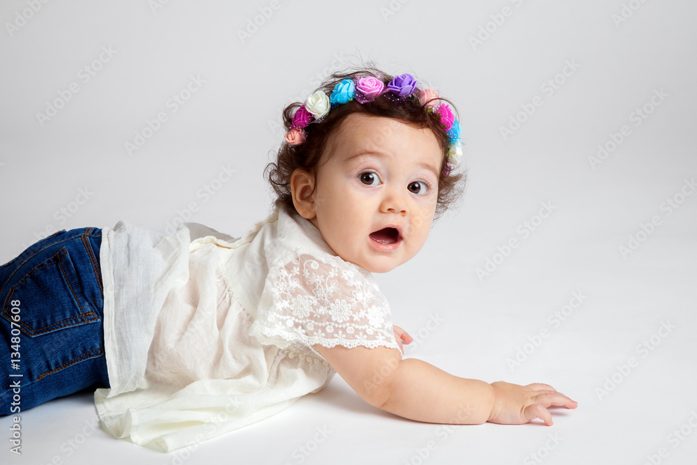 Adorable baby girl who looks shocked. She is laying on her stomach after falling while crawling. Adorable baby girl who looks shocked. She is laying on her stomach after falling while crawling.