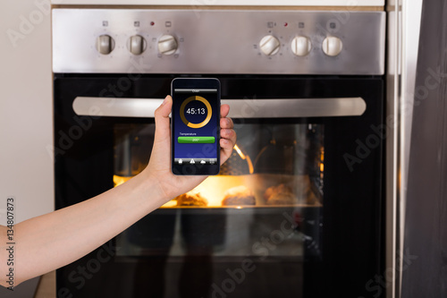 Person Operating Oven Appliance With Mobile Phone