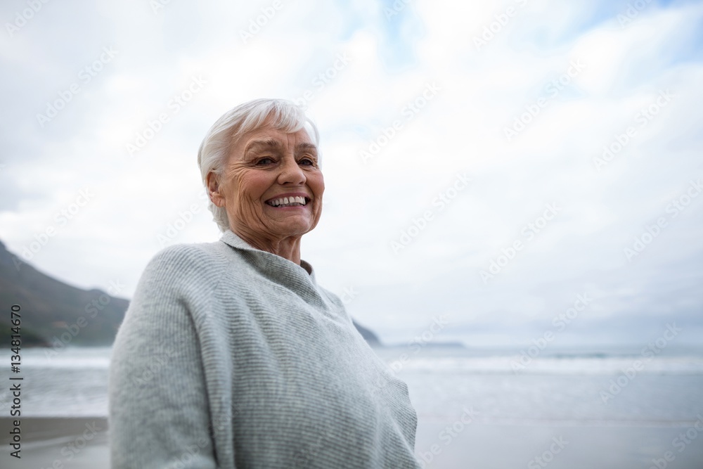 Fototapeta premium Portrait of senior woman standing on the beach