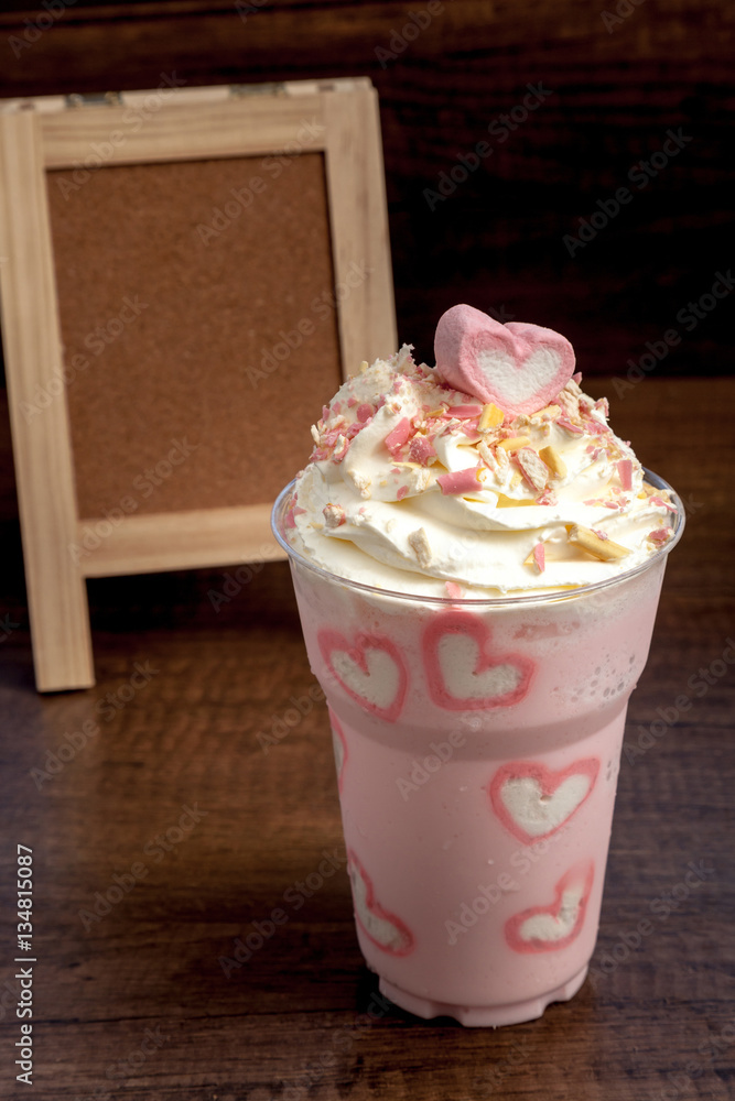 Pink milk shake with heart shape marshmellows topping on wooden