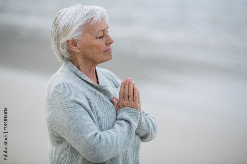 Fototapeta premium Senior woman praying on the beach