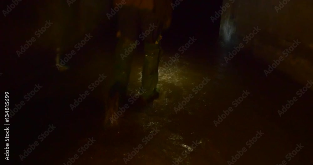 Legs in Chemsuit Boots go Along the Cave Waters, Which Are Dark, Dirty and Full of Slim, in Winter