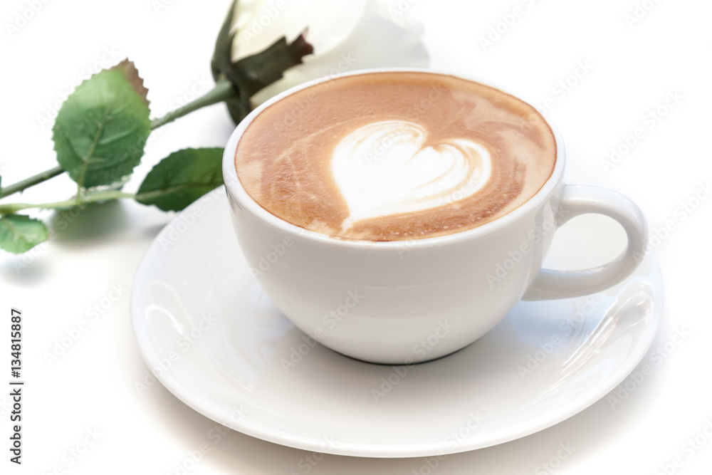 Coffee cup of heart shape latte art on the plate with white rose