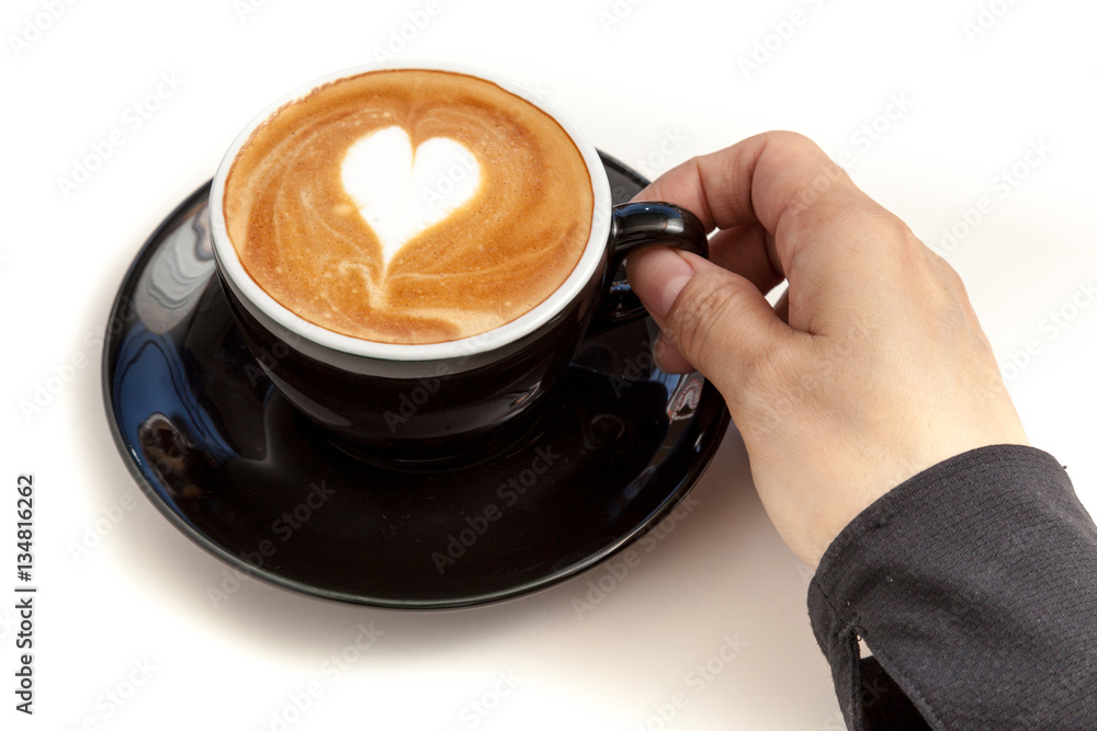Coffee cup with heart shape latte art on top, hand holding the c