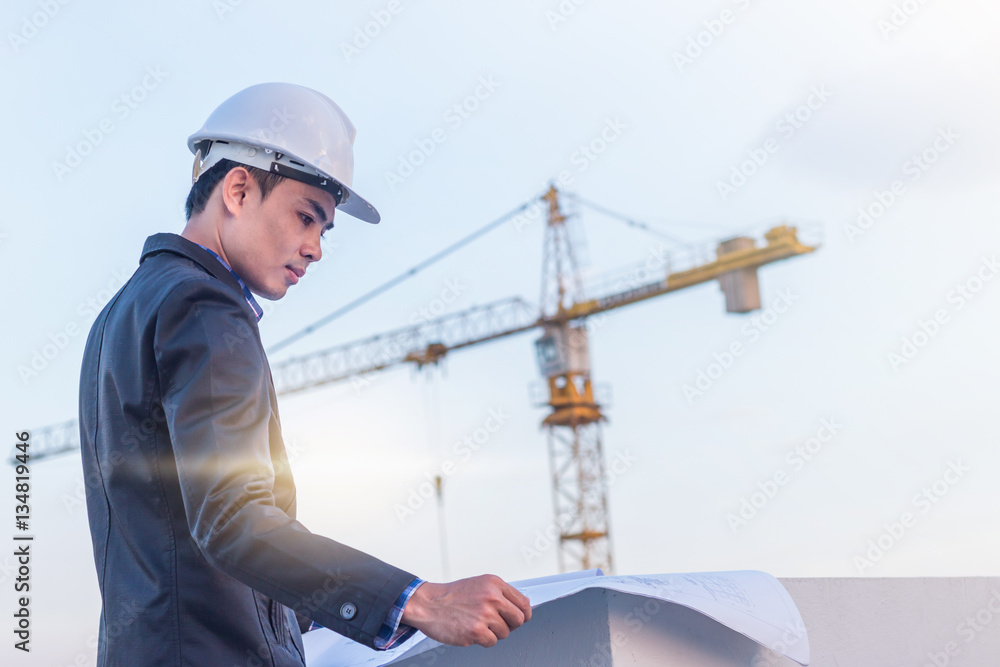The architect wear white safety helmet and verify the blueprint The architect wear white safety helmet and verify the blueprint