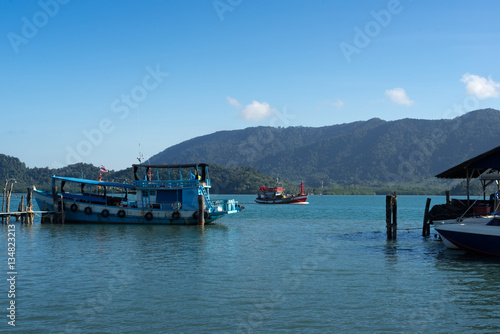 Red and blue fishing boats in sea with mountain background
