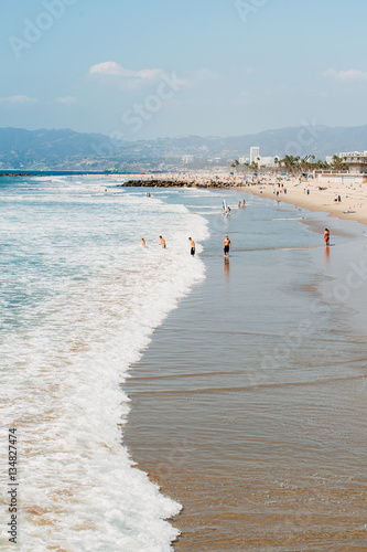 Pacific ocean coastline in Los Angeles USA. People walking at the beach. Ocean waves and foam.