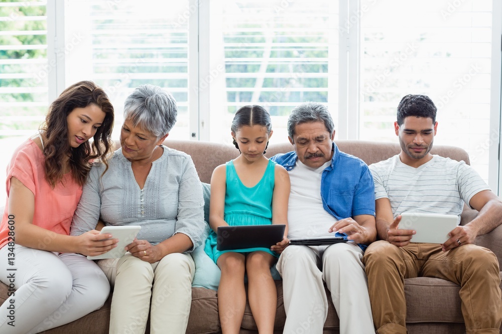 Multi-generation family using digital tablet in living room Multi-generation family using digital tablet in living room